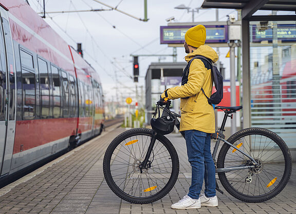 Ein Radfahrer steht mit seinem Fahrrad auf einem Bahnsteig. 