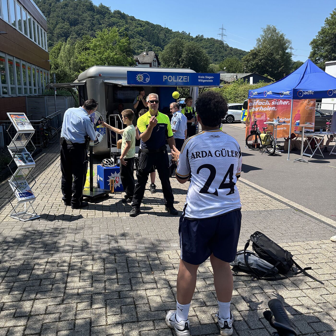 Ein Polizist und ein Schüler testen die Reaktionsfähigkeit bei einem Ballspiel mit einer Brille, die Betrunkenheit simuliert.